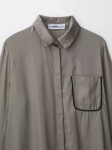 Detail of taupe long sleeve shirt featuring a pointed collar and black edged chest pocket