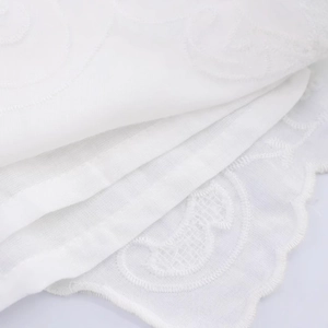 White cotton pajama shorts featuring intricate floral embroidery and scalloped edges