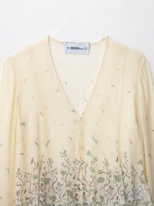 Détail de la blouse en mousseline à col en V avec imprimé floral et petits boutons