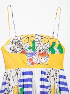 Detailed view of summer dress featuring tropical fruit prints and blue striped hem details