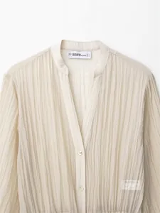 Detailansicht der beige plissierten Bluse mit feiner Stoffstruktur und kleinen Knöpfen