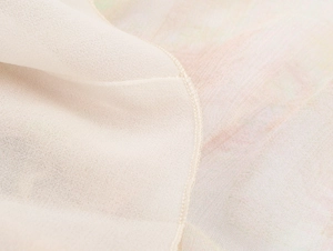Detail of cream pleated skirt fabric showing fine mesh weave and rolled hem stitching