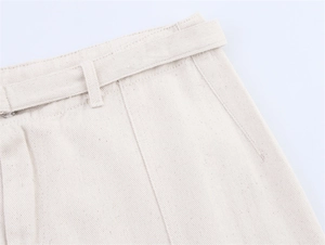 Detailed macro view of the beige denim waist featuring a fabric belt and clean stitching