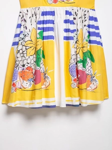 Close-up of artistic fruit and floral print hem on a yellow and white summer dress