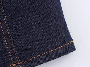 Detailed macro view of dark blue denim jacket fabric with orange double stitching