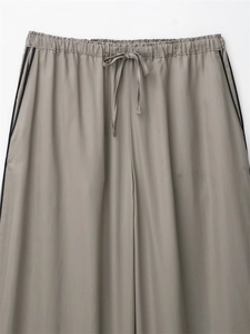 Detail of taupe wide-leg trousers featuring an elastic drawstring waist and side stripes