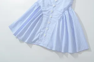 Detail view of light blue striped dress with white buttons and elegant pleated fabric texture