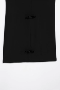 Detailed macro view of black woven dress featuring two elegant velvet bow decorations