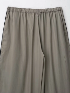 Detail of grey-brown wide-leg trousers with elastic waistband and side stripe accents