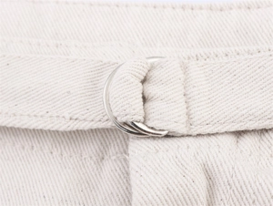 Detailed macro view of denim vest waist with metal D-ring belt and twill fabric texture