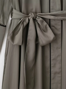 Dettaglio della vestaglia color taupe con bordi neri e una grande cintura a fiocco in vita