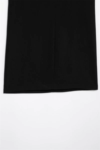 Detailed close-up of the smooth black fabric texture and hemline of the dress
