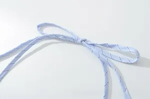 Detail of light blue striped halter neck tie with knotted craftsmanship and cotton texture