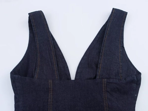 Detailed macro view of dark blue denim top with V-neck and contrast orange stitching