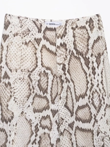 Close-up of snake print pants waist featuring zipper fly and beige animal pattern