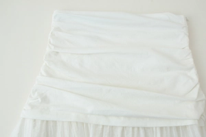 Gros plan sur le tissu froncé blanc avec détails plissés sur une jupe midi minimaliste