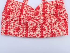 Detailed view of intricate red floral embroidery on a white lace cropped top