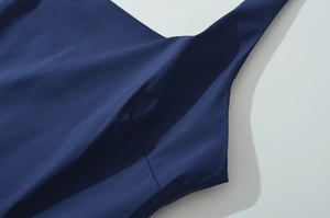 Detailed close-up of dark blue dress fabric showing fine texture and seamless stitching