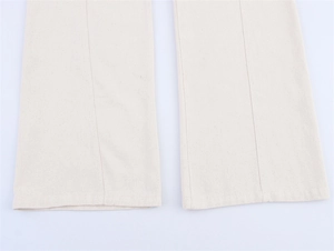Close-up of cream denim trousers featuring vertical decorative stitching and clean hem details