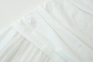 Gros plan d'une robe midi blanche montrant des plis détaillés et la texture du tissu