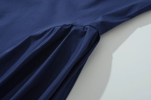 Detailed close-up of dark blue dress fabric featuring intricate pleating and stitching