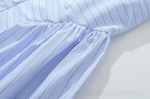 Detailed macro view of blue and white striped dress fabric with delicate pleats and button