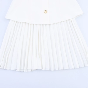 Detail of white pleated mini dress fabric featuring a round gold decorative button