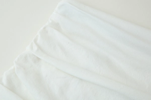 Gros plan détaillé sur la texture plissée blanche d'une robe midi de printemps en coton doux