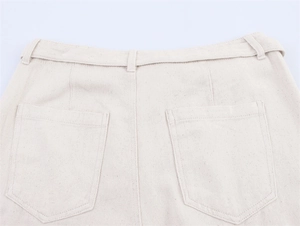 Detail of fabric texture and rear pentagonal pockets on casual off-white cotton shorts