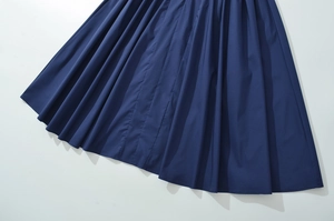 Detailed view of dark navy blue pleated hem with elegant drape and smooth fabric texture