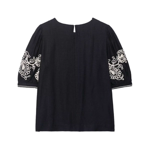Women's black short sleeve blouse featuring intricate white paisley floral embroidery and puff sleeves
