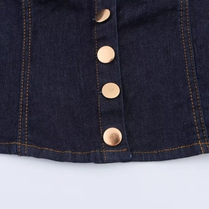 Detailed view of dark blue denim jacket with vintage gold buttons and yellow stitching
