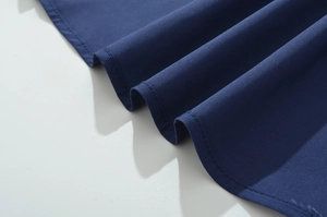 Detailed view of dark blue dress hem featuring precise stitching and cotton fabric texture