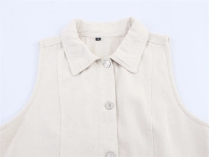 Close-up of cream white denim vest featuring metallic buttons and collar detail