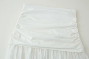 Détails d'une jupe mi-longue blanche avec fronces et couches de tissu plissées