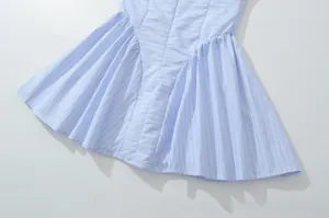 Detail of light blue striped dress hem featuring pleated design and crisp woven texture
