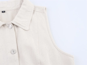 Close-up of cream denim vest featuring metal buttons and black neck size label