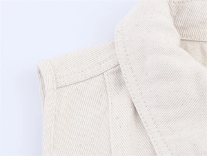 Detailed macro view of cream denim vest lapel featuring premium double-needle stitching
