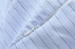 Detailed macro view of the invisible white zipper on blue striped dress fabric