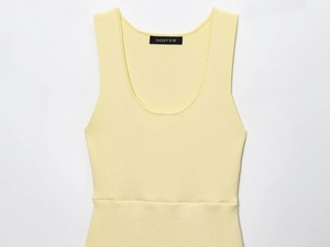 Detailed close-up of light yellow ribbed knit fabric texture and round neckline stitching