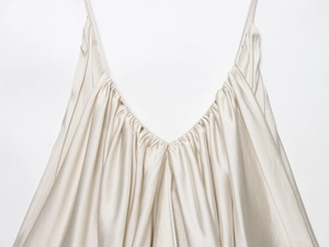 Detailed close-up of champagne satin top with pleated V-neck and delicate straps