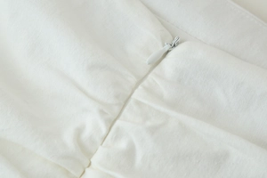 Détail d'un zip invisible sur une robe midi blanche en coton avec des plis