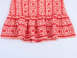Close-up of white cotton skirt with red floral embroidery and ruffled hem details