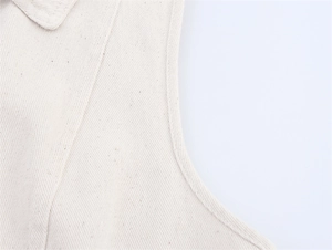 Close-up of beige denim vest showing raw cotton canvas texture and reinforced seam stitching