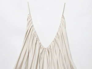 Detail of cream silk satin top featuring thin straps, deep V-neckline and ruched texture