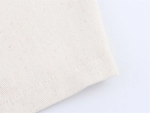 Macro shot of off-white twill denim fabric with precise stitching and natural cotton texture