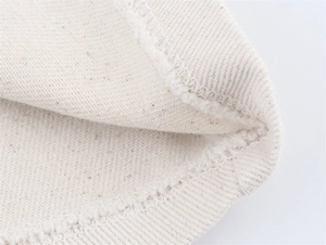 Macro detail of twill denim fabric texture and neat overlock stitching on off-white set