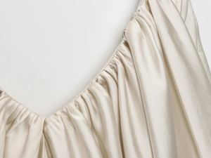 Detailed macro view of champagne satin fabric texture with elegant gathered pleats