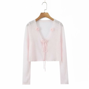 Close-up of pink sheer bolero cardigan with floral crochet lace and front ribbon ties