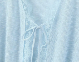 Close-up of light blue knit cardigan featuring delicate lace trim and soft tie closure
